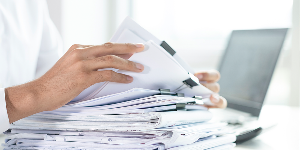 stacks of papers with someone working on them